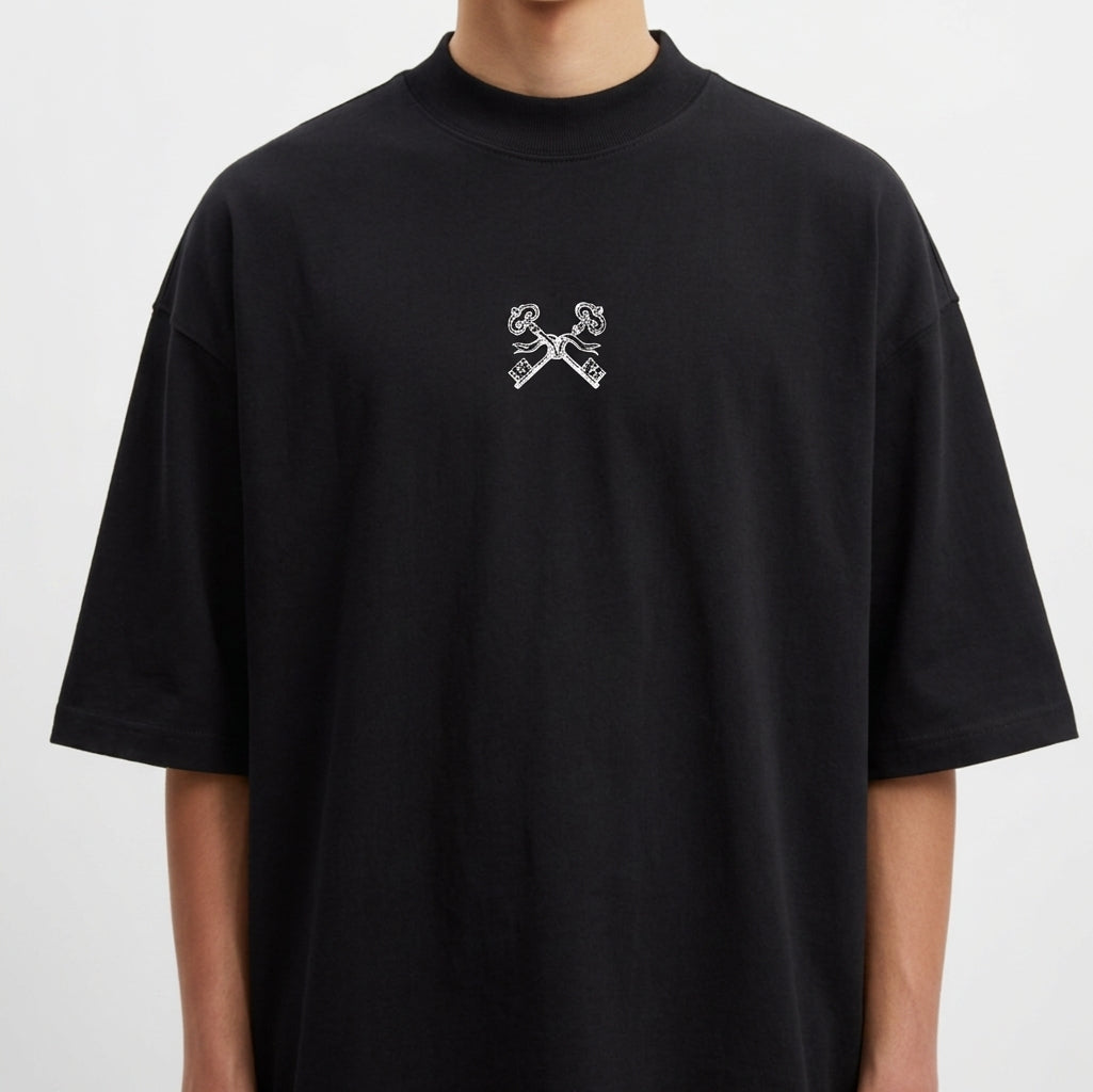 Camiseta com estampa frontal de duas chaves cruzadas e estampa traseira de mão segurando um bastão com a frase "FIRMEZA! primeiro se firma. depois se caminha."