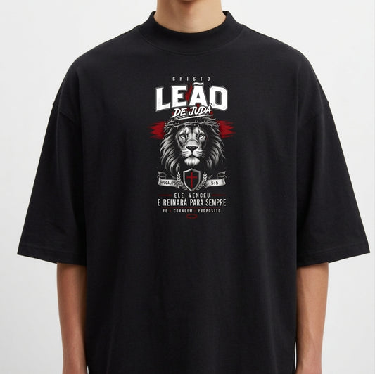 Camiseta com estampa frontal de um leão acompanhado de texto "Cristo Leão de Judá", escudo e datas, destacando simbolismo religioso e força.