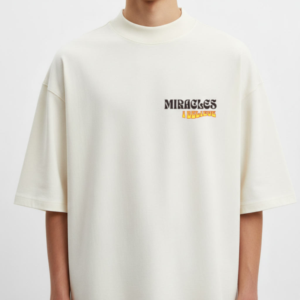 Camiseta com estampa frontal de texto "MIRACLES I BELIEVE" em fonte estilizada e traseira de texto "NUNCA VIMOS NADA IGUAL" com variação de cores e tamanhos.