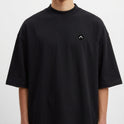 Camiseta com estampa frontal de círculo minimalista e estampa traseira de retrato feminino artístico em tons vibrantes com palmeiras e pôr do sol ao fundo.