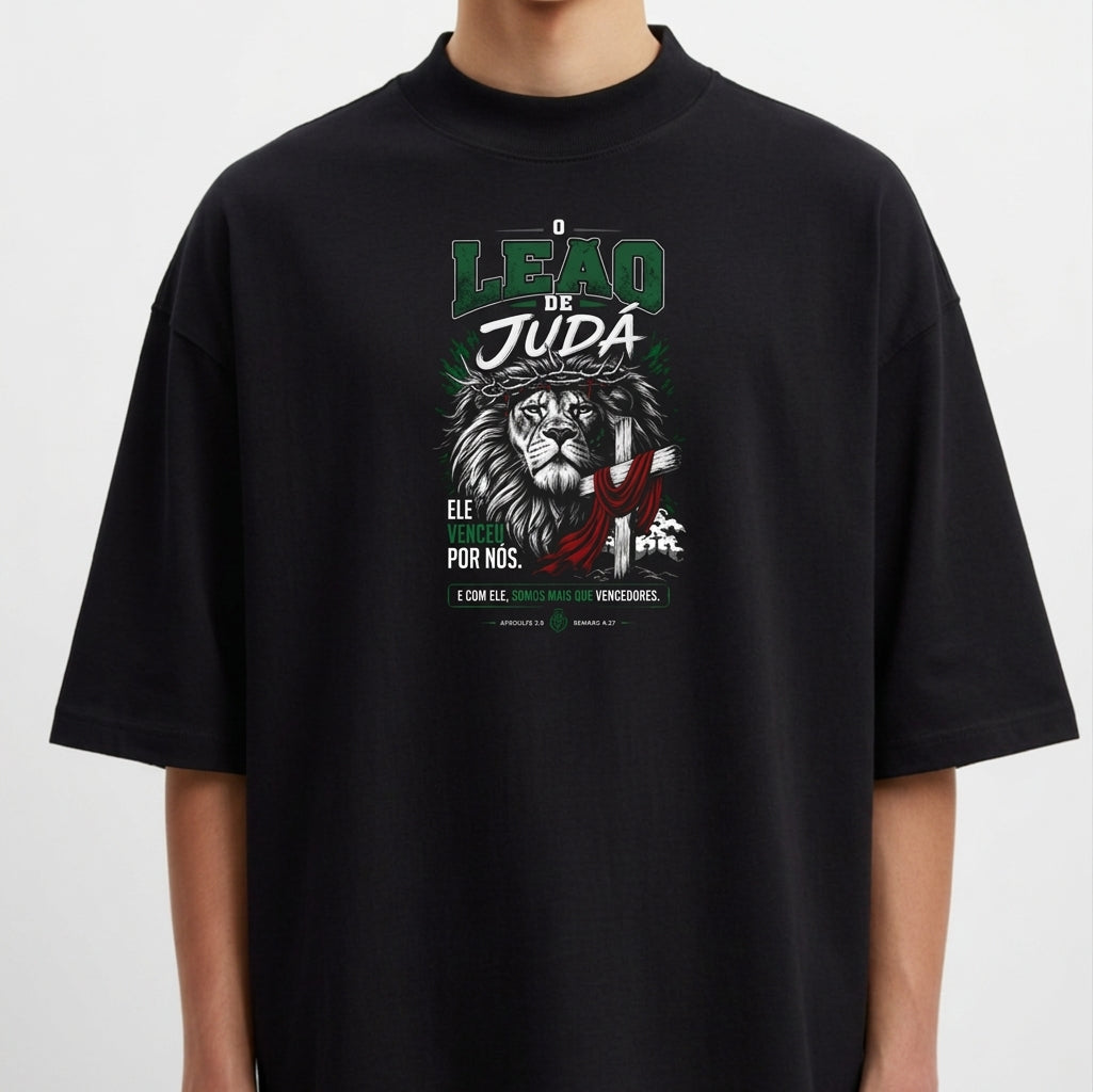 Camiseta com estampa frontal de leão com detalhes gráficos, textos destacando 'Leão de Judá' e frases adicionais em estilo tipográfico.
