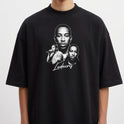 Camiseta com estampa frontal de três retratos detalhados de um artista em diferentes poses, com um nome em estilo caligráfico destacado abaixo.
