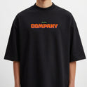 Camiseta com estampa frontal de texto "COMPANY" em relevo e estampa traseira de ilustração artística com rostos repetidos sobre fundo geométrico.