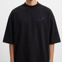 Camiseta com estampa frontal de traço curvado estilizado e estampa traseira de três máscaras teatrais, com uma sorrindo e duas expressando tristeza.