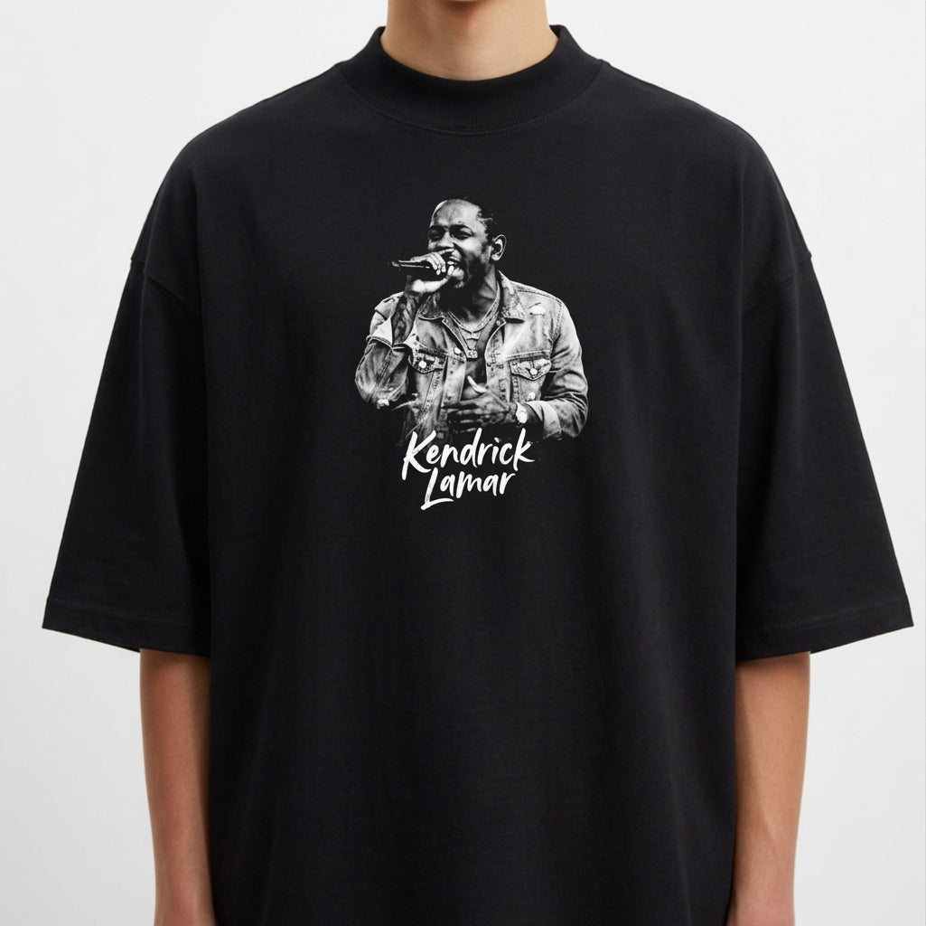 Camiseta com estampa frontal de um cantor segurando um microfone, exibindo detalhes de uma jaqueta e um nome logo abaixo em fonte estilizada.