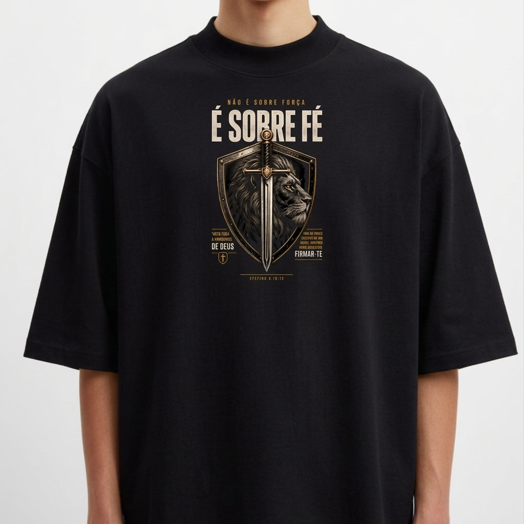 Camiseta com estampa frontal de escudo contendo uma espada centralizada e a imagem de um leão ao fundo, com textos ao redor enfatizando fé.