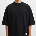 Camiseta com estampa frontal de pequeno logotipo minimalista e estampa traseira de ilustração artística de rosto masculino entrelaçado com elementos geométricos e tribais.