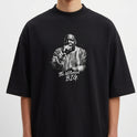 Camiseta com estampa frontal de um artista segurando um microfone e trajando roupa detalhada, acompanhada da inscrição estilizada "The Notorious B.I.G.".
