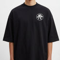 Camiseta com estampa frontal de logotipo com personagem e texto "BOY BIGORNA" e estampa traseira de personagem robótico em pose imponente com nome acima.