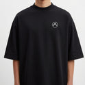 Camiseta com estampa frontal de símbolo minimalista circular com seta apontando para cima e estampa traseira de paisagem tropical com palmeiras e pôr do sol refletido no mar.