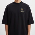 Camiseta com estampa frontal de desenho de um passarinho dentro de uma gaiola estilizada com a inscrição "Máquina Voadora" abaixo do desenho.