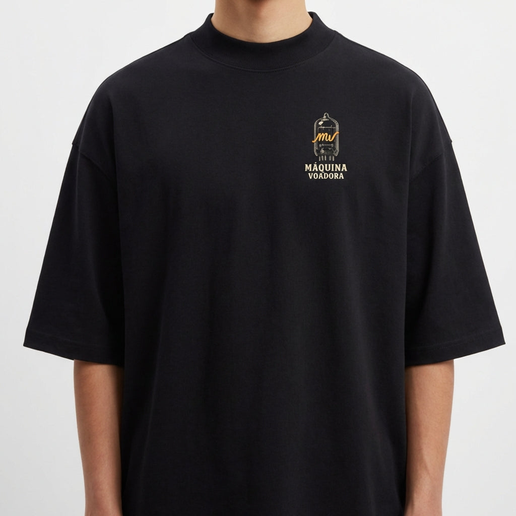 Camiseta com estampa frontal de desenho de um passarinho dentro de uma gaiola estilizada com a inscrição "Máquina Voadora" abaixo do desenho.