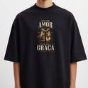Camiseta com estampa frontal de uma cruz entre colunas clássicas, rodeada por folhagens e frase "Foi por amor, vivo pela graça - Efésios 2:5".