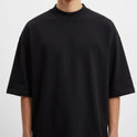 Camiseta com estampa frontal de pequeno logotipo estilizado e estampa traseira de personagem em quadrinhos com frase em destaque e elementos gráficos.