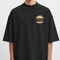 Camiseta com estampa frontal de coroa de espinhos detalhada e estampa traseira de figura angelical segurando uma espada, acompanhada de tipografia estilizada.