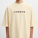 Camiseta com estampa frontal de texto estilizado "LUNOVA" em tipografia limpa e moderna e estampa traseira de anjo detalhado com asas amplas e a inscrição "FREEDOM AND PEACE".
