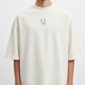Camiseta com estampa frontal de rosto estilizado e estampa traseira de figuras sombrias sobrepostas, incluindo um lobo feroz e uma personificação misteriosa.