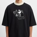 Camiseta com estampa frontal de dois personagens sentados com um dispositivo, um dos personagens sorridente e mãos aos ombros, e estampa traseira de gaiola minimalista com texto pequeno.