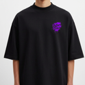 Camiseta com estampa frontal de lettering estilizado em roxo com traços pontiagudos e efeito de escorrimento, proporcionando um visual marcante e moderno.