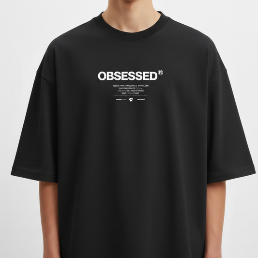 Camiseta com estampa frontal de texto grande "OBSESSED" e abaixo uma sequência de textos menores combinando palavras e símbolos minimalistas.