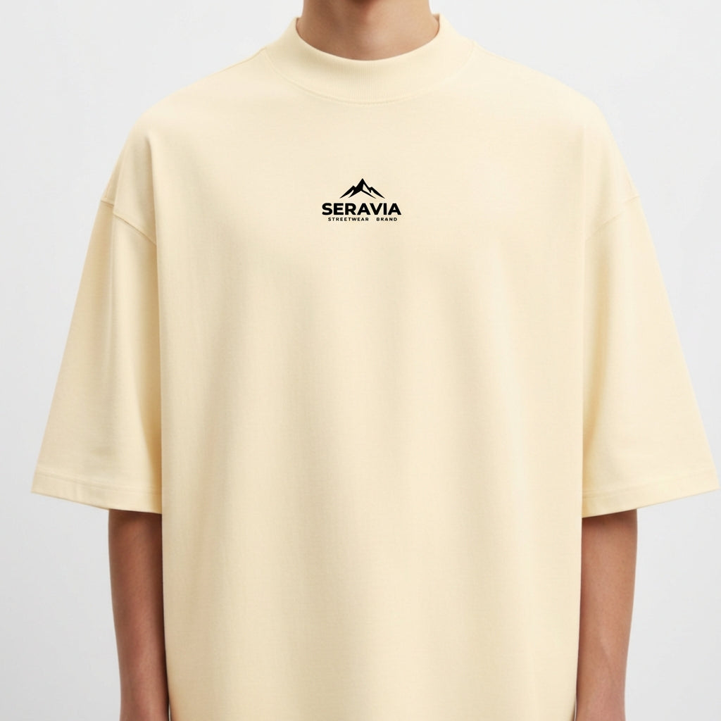 Camiseta com estampa frontal de montanha e texto sob ela, e estampa traseira detalhada de figura mitológica central cercada por caveiras e chamas.