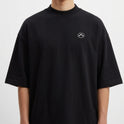 Camiseta com estampa frontal de símbolo minimalista e estampa traseira de pranchas de surfe em fundo de pôr do sol com palmeiras e chão xadrez.