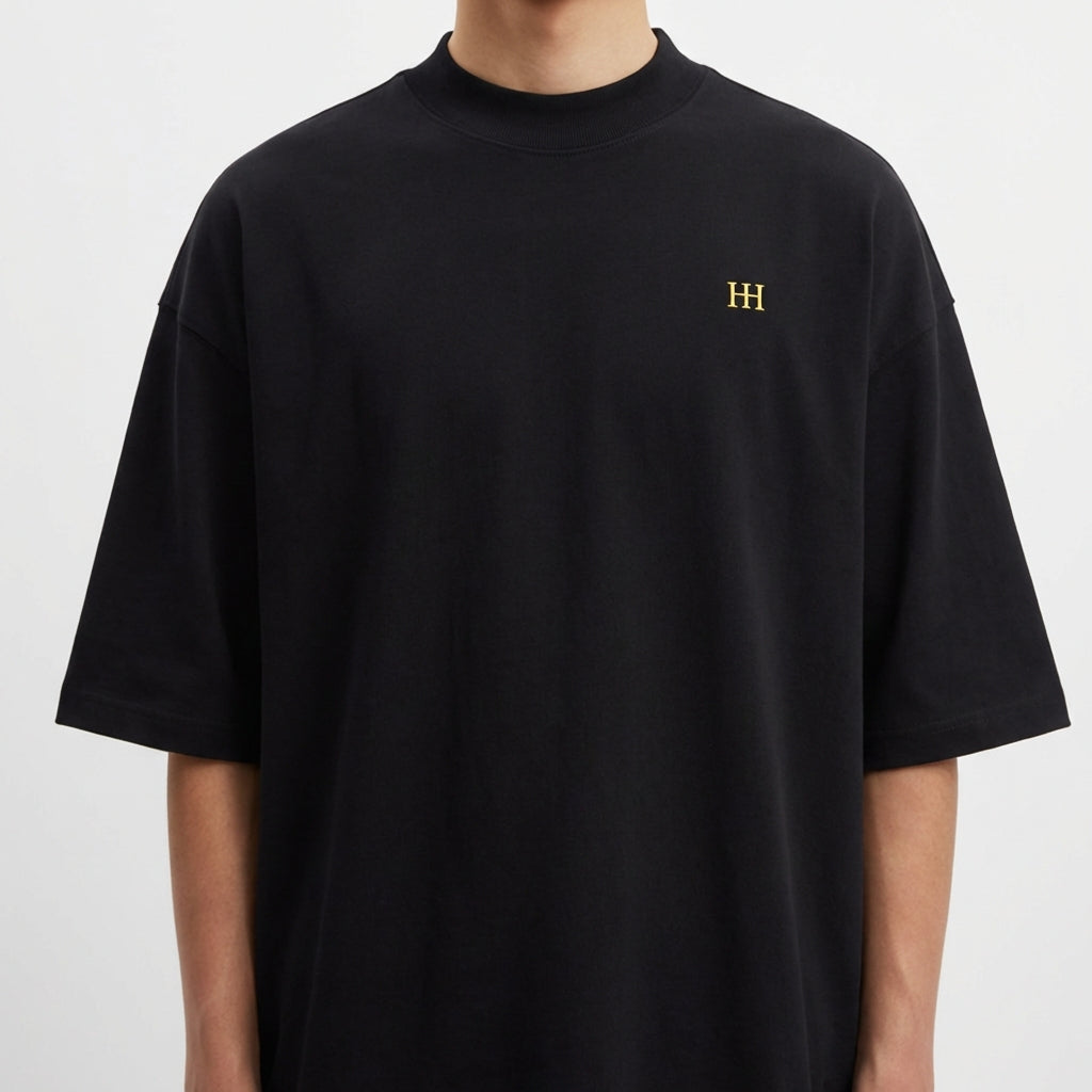 Camiseta com estampa frontal do monograma "H" minimalista e estampa traseira de imagem artística com mãos semelhantes a "A Criação" e texto "Born from Caffeine".