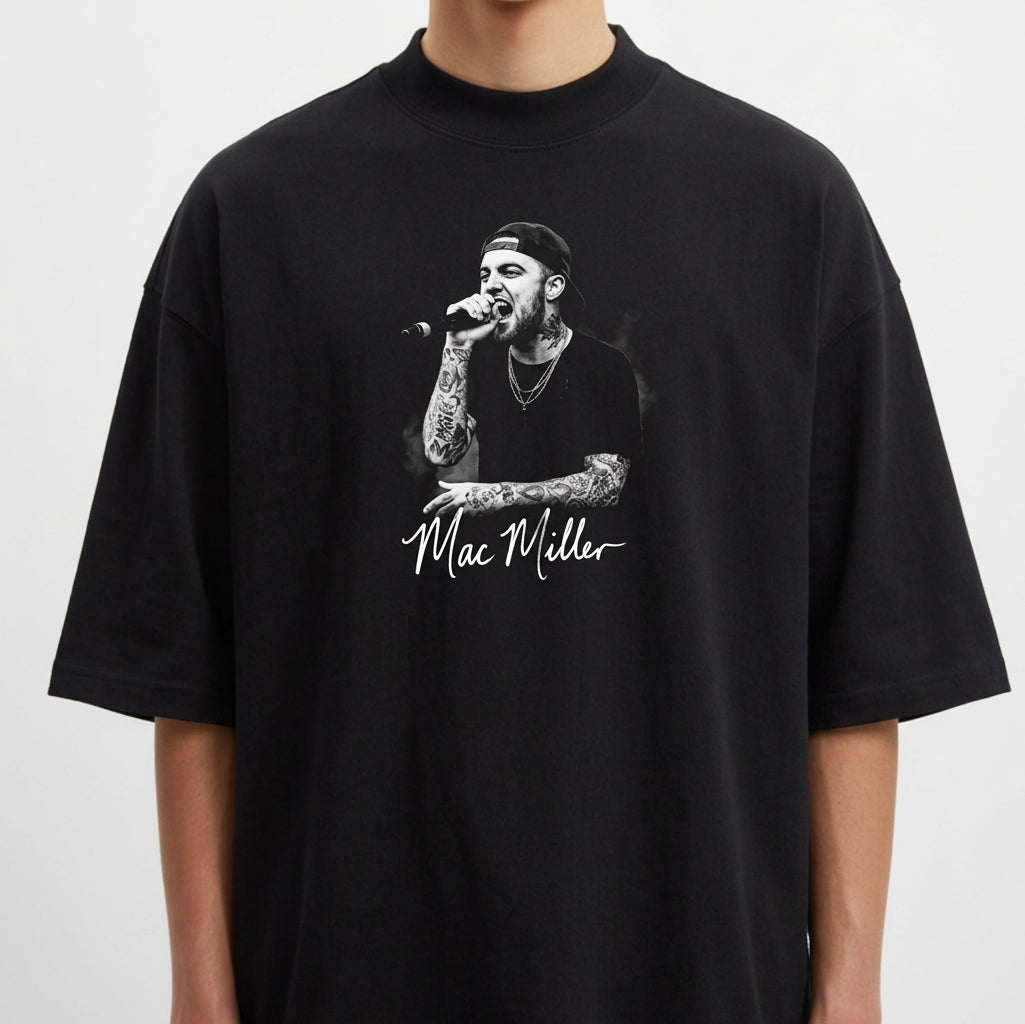 Camiseta com estampa frontal de um artista cantando no microfone, vestindo boné e camisa preta, destacando tatuagens nos braços e autógrafo abaixo.