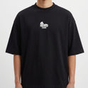 Camiseta com estampa frontal de uma estrutura arqueológica e estampa traseira de figura religiosa carregando uma cruz com a palavra "JESUS" em destaque.