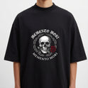 Camiseta com estampa frontal de caveira detalhada rodeada por espinhos, acompanhada de uma rosa e as palavras “Memento Mori” na parte superior e inferior.