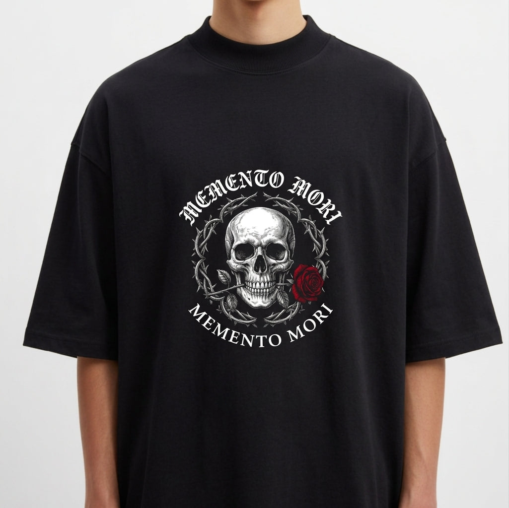 Camiseta com estampa frontal de caveira detalhada rodeada por espinhos, acompanhada de uma rosa e as palavras “Memento Mori” na parte superior e inferior.