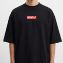 Camiseta com estampa frontal de texto dentro de retângulo pequeno, e estampa traseira de texto pequeno localizado próximo à gola.