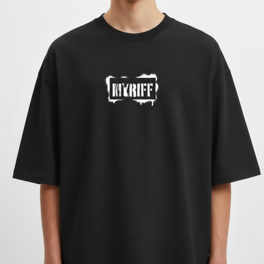 Camiseta com estampa frontal de letras em estilo stencil, com aparência desgastada e elementos como respingos ao redor, trazendo um visual urbano.