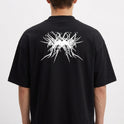 Camiseta com estampa frontal de "Pantano 3000" em letras estilizadas, e estampa traseira de design abstrato com elementos pontiagudos entrelaçados.