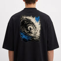 Camiseta com estampa frontal de pequeno símbolo circular com seta apontando para cima no lado esquerdo do peito e estampa traseira de surfista em túnel de onda dinâmica com efeitos de pinceladas.