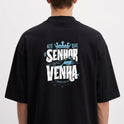 Camiseta com estampa frontal de texto cursivo "Verbo" e estampa traseira de coroa, montanhas, estrela e frases expressivas em texto impactante.