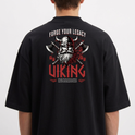 Camiseta com estampa frontal de pequeno símbolo gráfico e estampa traseira de figura viking com capacete e machados cruzados, acompanhada de inscrições temáticas.
