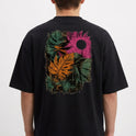 Camiseta com estampa frontal de pequeno logotipo minimalista e estampa traseira de folhas tropicais em diversas cores e círculo texturizado.