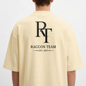 Camiseta com estampa frontal de lettering cursivo "Racoon Team - Built Different" e estampa traseira de iniciais grandes "RT", texto "Raccon Team - Est. 2017".