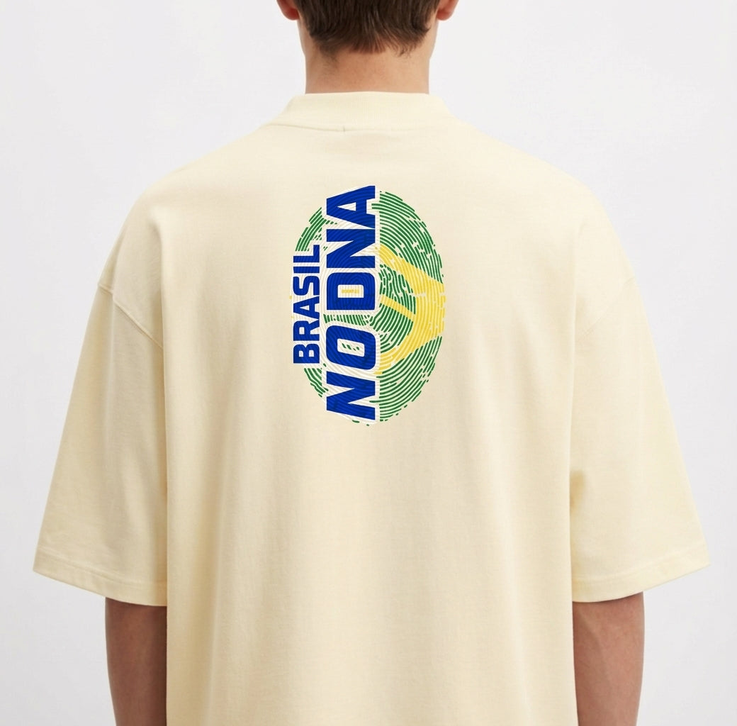 Camiseta com estampa frontal de uma pequena impressão digital acompanhada do texto "Brasil no DNA" e estampa traseira maior do mesmo padrão.