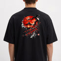Camiseta com estampa frontal de texto "LUNOVA" com símbolo acima e estampa traseira de lanterna japonesa sob árvore de cerejeira com lua vermelha ao fundo.