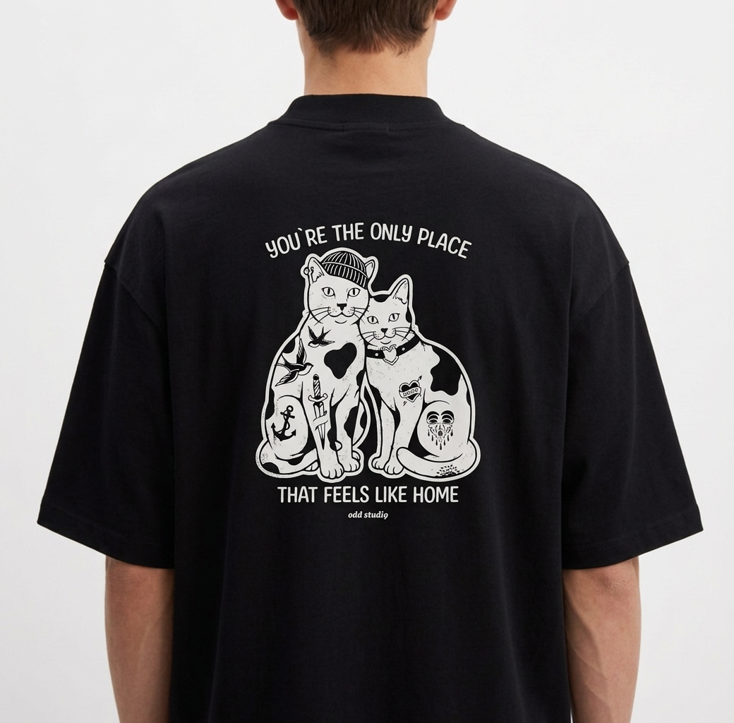 Camiseta com estampa frontal de duas cabeças de gatos em estilo ilustrativo e estampa traseira de dois gatos sentados rodeados por detalhes artísticos.