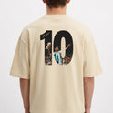 Camiseta com estampa traseira de número grande "10" ilustrando jogador em ação segurando troféu, com assinatura sobreposta e multidão ao fundo.