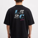 Camiseta com estampa frontal de “L5 2C” em estilo pixelizado e texto menor em roxo, e estampa traseira ampliada do mesmo texto com caracteres adicionais.