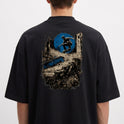 Camiseta com estampa frontal de logo minimalista circular e estampa traseira de skatista sobre ruínas urbanas e círculo abstrato.