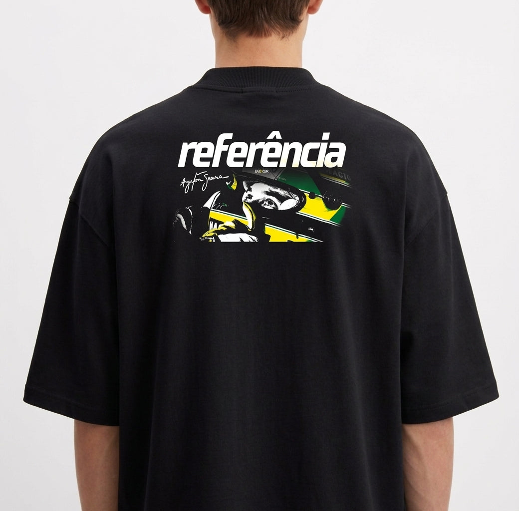 Camiseta com estampa frontal de elementos abstratos estilizados e fragmentos de rosto e estampa traseira de piloto de corrida com capacete e assinatura.