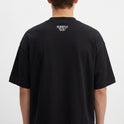 Camiseta com estampa frontal de texto dentro de retângulo pequeno, e estampa traseira de texto pequeno localizado próximo à gola.