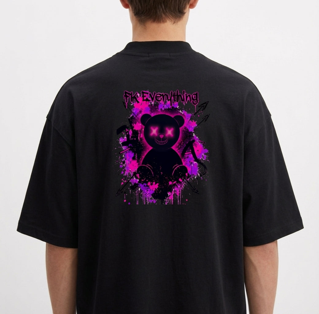 Camiseta com estampa frontal de inscrição estilizada e estampa traseira de urso sorridente com olhos em forma de "X" sobre fundo de respingos vibrantes.
