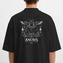 Camiseta com estampa frontal de "Seravia" em letras estilizadas e detalhe ornamental, e estampa traseira de Anúbis, o deus egípcio, com asas e tochas.