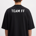 Camiseta com estampa frontal de texto estilizado "TïFF" e estampa traseira de "TEAM FF" em letras maiúsculas.